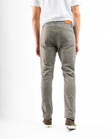 Pantalón de gabardina color beige, de corte recto, con bolsillos laterales y traseros. Se ajusta a la cintura con cinturón de cuero marrón.