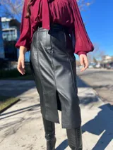 Falda midi color caramelo de cuero sintético, corte recto, con abertura frontal y cinturón con hebilla dorada.