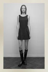 Vestido negro sin mangas, con escote redondo y falda corta plisada.