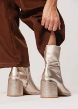 Bota de caña media color champagne de cuero, con horma redonda, taco cuadrado y pequeña plataforma. Cuenta con cierre del lado interno.