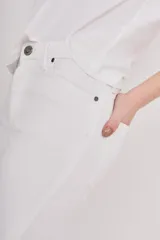 Pantalón jean blanco de corte slim, tiro alto y terminación desflecada en el ruedo.