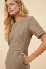 Vestido marrón de lana fina sin teñir, con corte a la rodilla, mangas cortas y cuello redondo.