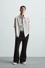 Pantalón negro de algodón con corte relajado y pierna ancha (flare fit). Presenta cierre frontal con botón y cremallera, bolsillos delanteros y bolsillos traseros de plastrón.