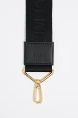 Correa bandolera ajustable de tejido negro con el logo de Bimba y Lola en jacquard. Tiene detalles en piel vacuna negra y herrajes metálicos dorados.