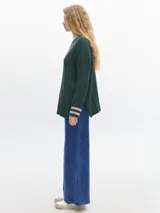 Buzo verde oscuro de tejido de punto con cuello alto y mangas largas. Tiene un pequeño logo bordado en el pecho y puños y cuello en color beige con rayas horizontales.