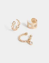 Set de tres aros dorados para la oreja, tipo cuff, con diferentes diseños: uno liso con calados de corazón, uno con eslabones y uno con strass colgante.
