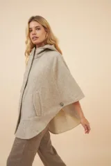 Capa amplia color marrón con capucha, cierre metálico y bolsillos delanteros. Espalda con canesú y botones laterales para generar la manga.