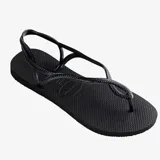Ojotas Havaianas modelo Luna, color negro, con tiras finas que se cruzan y forman un diseño trenzado que rodea el tobillo. La suela es texturizada con el logo de la marca en relieve.