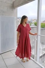Vestido de manga corta, color rojo oscuro (bordeaux), con escote en V y corte acampanado que termina en un bajo asimétrico con detalle deshilachado.