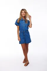 Mono corto de jean azul con cuello camisero, cierre frontal con botones, mangas cortas con dobladillo y bolsillos delanteros y traseros.
