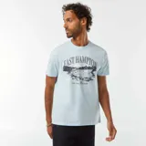 Camiseta celeste de manga corta con cuello redondo. Estampado frontal con el texto "East Hampton New York - United States" y un dibujo de un yate.