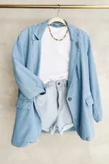 Blazer celeste de denim con solapas, cierre de un botón y bolsillos frontales.