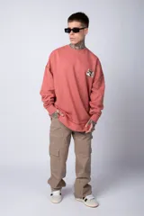 Buzo color crema de corte oversize confeccionado en tela friza con cuello redondo y puños y cintura acanalados. Presenta un pequeño bordado en el frente y un estampado grande en la espalda.