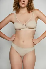 Conjunto de lencería color beige, compuesto por un corpiño sin aro con detalle de tul en la parte superior y una bombacha tipo colaless.