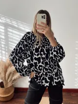 Sobrecamisa de plush con estampado animal print en blanco y negro, con cuello camisero, cierre frontal con botones, mangas largas abullonadas y bolsillos laterales.