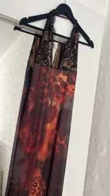 Vestido largo de microtul con estampado abstracto en tonos marrones, azules y naranjas. Tiene escote en V con encaje negro y breteles finos.