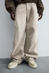 Pantalón de jean color beige, de corte amplio y tiro alto, con cinco bolsillos, efecto lavado y cierre frontal con botones.