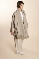 Saco de lana color marrón claro, con mangas amplias, cuello tipo bufanda con flecos y bolsillos laterales. Diseño oversize sin forro.