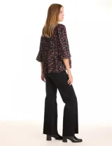 Blusa de gasa estampada en color negro con motivos rojos y blancos, de cuello a la base con escote en V y manga larga con terminación fruncida.