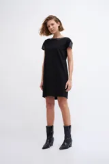 Vestido negro de corte recto y manga corta, con cuello y hombros con apliques de cuero ecológico negro.