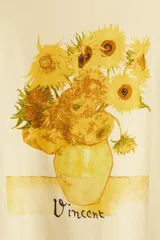 Remera color crema de corte amplio con estampado de girasoles en un jarrón y la firma 'Vincent'.