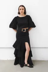 Falda larga negra de tafeta con cintura ajustada, tajo lateral y volados escalonados.