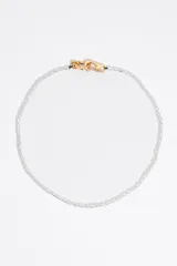 Collar de perlas blancas irregulares con cierre de mosquetón dorado y dije de corazón dorado.