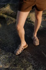 Sandalias tipo mule de cuero color marrón chocolate, con diseño de tiras anchas cruzadas y suela plana.