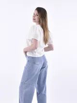 Blusa color blanco con mangas cortas abullonadas y calado con pequeños orificios.
