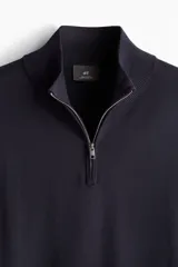 Buzo de punto fino azul marino con cuello alto acanalado y medio cierre. Corte ajustado.