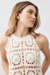 Top tejido crochet color crudo, con cuello halter y espalda descubierta.