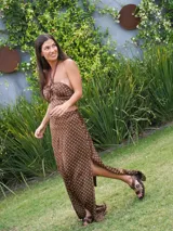 Vestido largo marrón con lunares blancos, escote halter con lazo trenzado al cuello y aberturas en la cintura y en la falda.