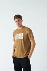 Remera color ocre de corte recto y manga corta, con cuello redondo y estampado rectangular con diseño floral en el frente.