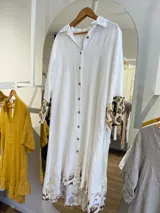 Vestido camisero largo de lino color beige con botones frontales, cuello camisero y mangas largas con puños. Presenta estampado animal print en mangas y ruedo.