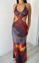 Vestido largo con estampado abstracto en tonos marrones, rojos y grises. Diseño ajustado con escote halter y aberturas laterales en la cintura.