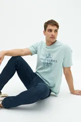 Remera verde agua de manga corta con estampado de dos peces y texto en azul marino.