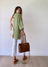 Cartera bandolera de cuero color tostado, con correa larga regulable, bolsillo frontal y forro de tela.