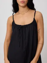 Vestido corto de algodón y lino color negro, con tirantes finos y escote recto con lazo ajustable.