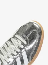 Zapatillas Adidas Samba OG W plateadas metalizadas con efecto craquelado, las tres tiras laterales blancas y suela de goma color caramelo.
