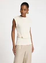 Musculosa color crema de algodón con cuello redondo y tirantes anchos. Presenta una banda fruncida en el frente con detalle de argolla metálica lateral.