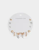 Set de seis pares de aros dorados con distintos diseños: aros tipo botón con perla, aros tipo botón con strass, aros tipo botón dorados, aros de argolla y aros colgantes con dije de perla y moño.