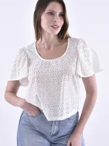 Blusa blanca de corte cropped, con detalles de calados y mangas cortas abullonadas.