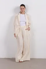 Pantalón palazzo color crema de lino con pinzas, de calce relajado y tiro alto.