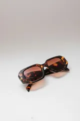 Lentes de sol rectangulares con marco de carey y lentes marrones.