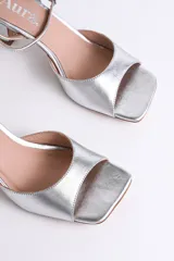 Sandalia plateada de fiesta con diseño elegante y minimalista. Presenta punta cuadrada, tira delantera ancha y pulsera al tobillo con hebilla regulable, que brinda firmeza y comodidad.