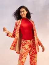 Blazer color crudo con estampado de hojas rojas, de corte recto y solapas clásicas.