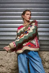 Sweater de lana color crema con cuello redondo, mangas largas y diseño tejido con motivos geométricos y florales en tonos marrones, rojos, verdes, azules y rosas.