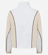 Campera deportiva de mujer, color blanco y beige, con cuello alto y cierre frontal. Presenta frisos contrastantes en color marrón que definen el diseño de bloques de color en el torso y mangas.