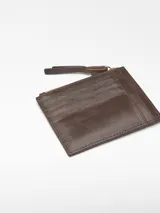 Monedero mediano de piel craquelada color marrón, con curtición vegetal. Tiene un compartimento con cierre de cremallera, tarjetero en la parte trasera y logo grabado.