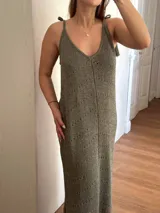 Vestido largo tejido con hilo de algodón y lurex color verde oliva. Silueta trapecio, escote en V, tiras regulables con borlas, espalda abierta y tajos laterales.